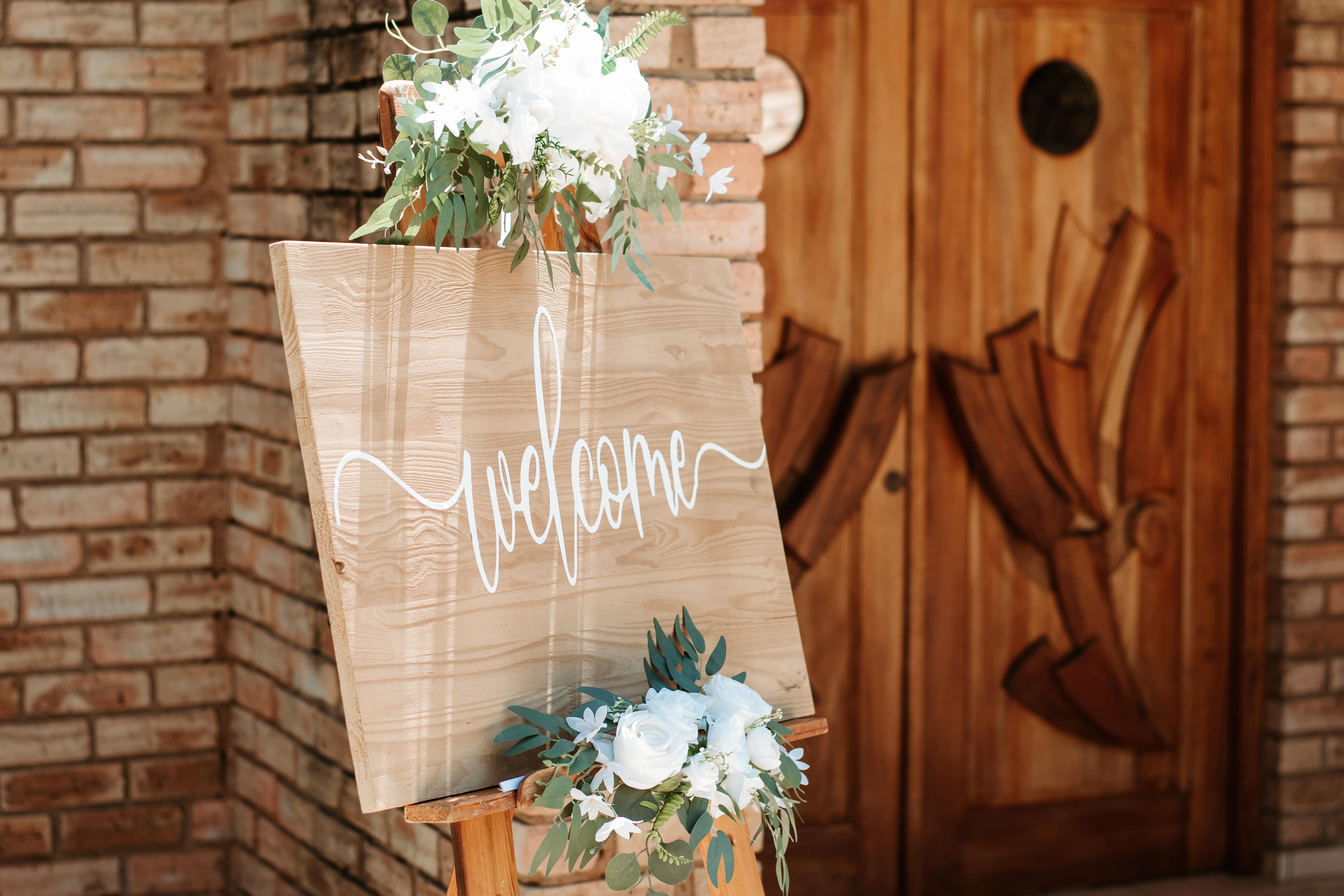 wooden welcome sign easel with floral arrangements and chalkboard