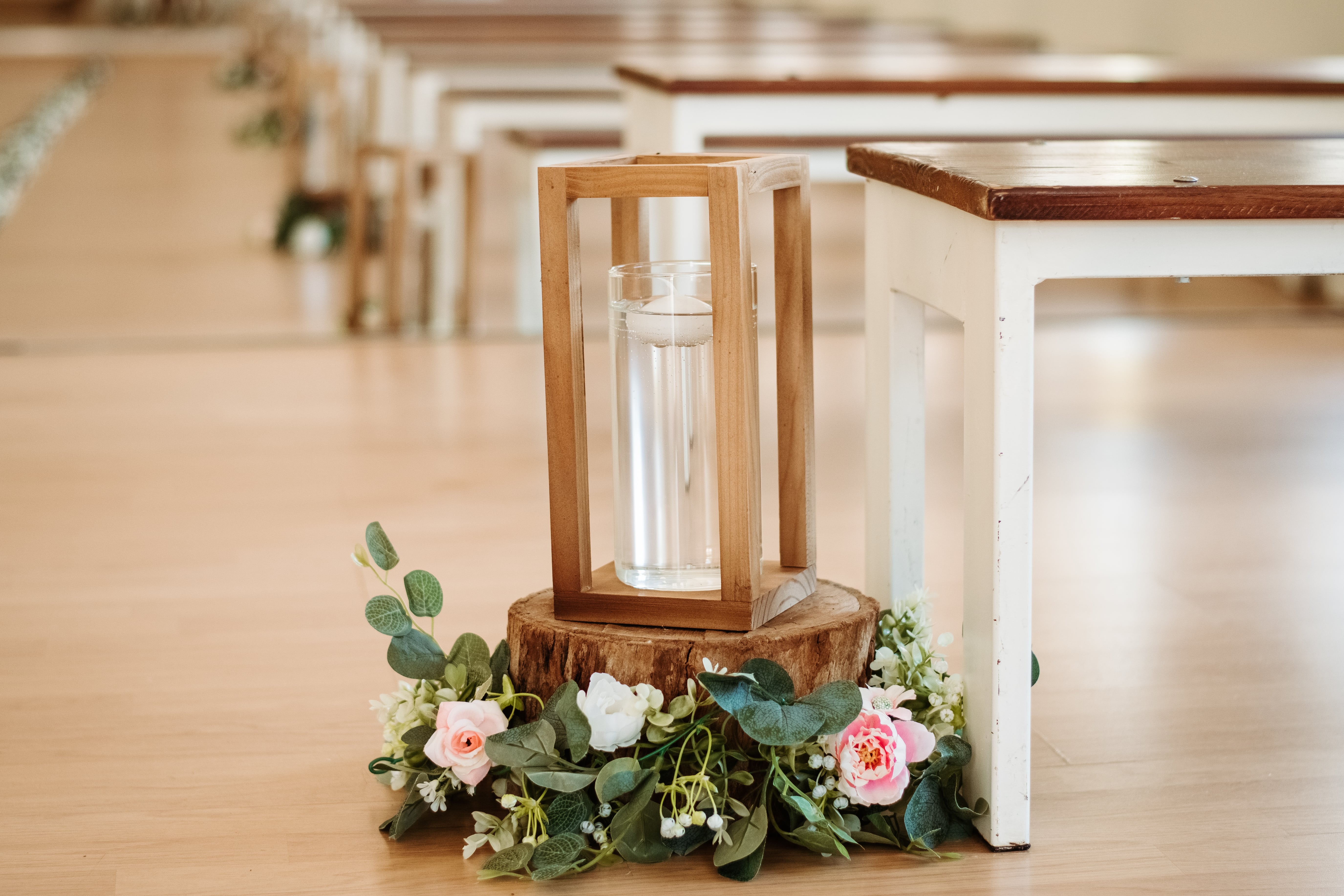 wooden lantern on log base with eucalyptus and pink roses
